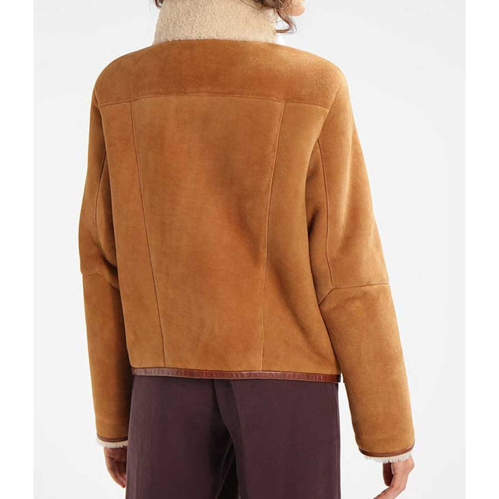 A person shown from the back wearing a camel brown suede jacket with a cream-colored fuzzy collar and dark plum trousers, against a plain white background.