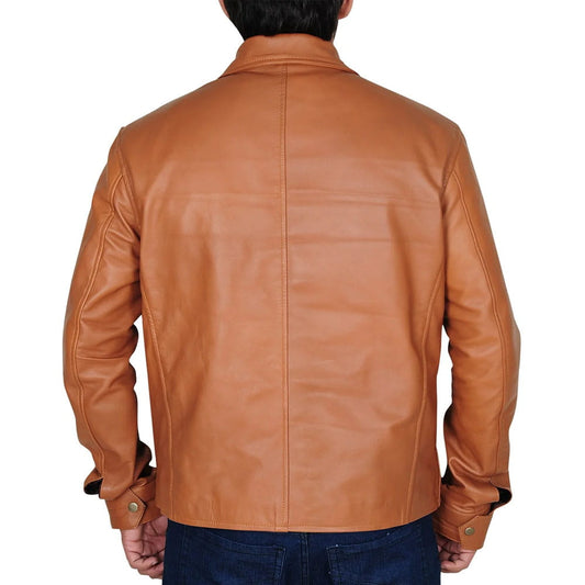 A man viewed from the back wearing a tan leather jacket and dark blue jeans against a plain white background.