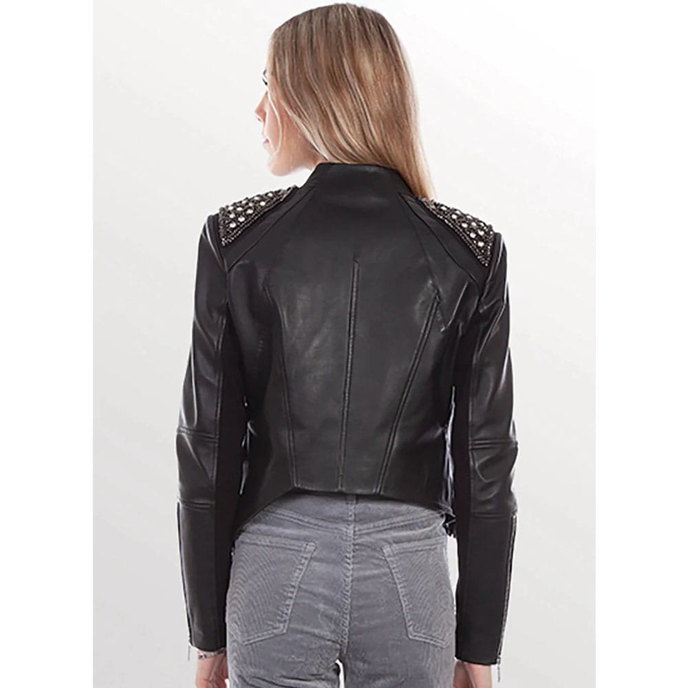 A woman shown from the back wearing a black leather moto jacket with silver studded shoulder details, paired with gray jeans, against a plain white studio background.
