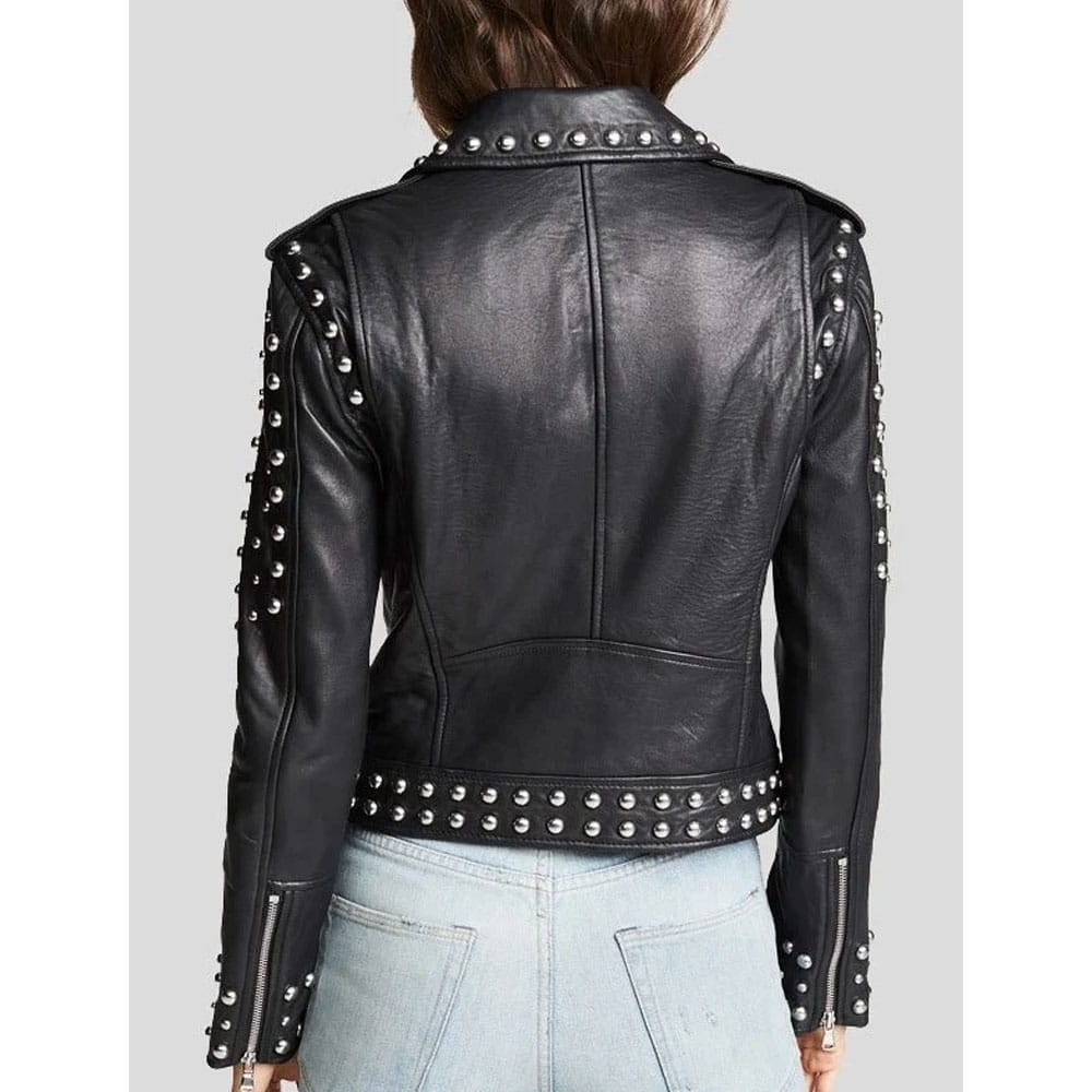 A black leather moto jacket with silver studs and zippers, shown from the back on a model wearing light blue jeans against a gray background.