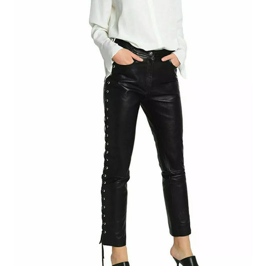 A person wearing black faux-leather cropped pants with side lace-up detailing, paired with a white blouse and black heels, shown against a plain white background.