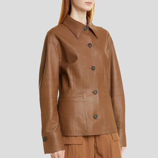 A woman wearing a brown faux-leather utility jacket with dark buttons, shown from the neck down against a solid light gray background.