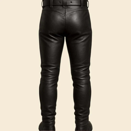 Black leather pants shown from the back, featuring a belt loop waist and slim tapered legs, on a solid beige background.