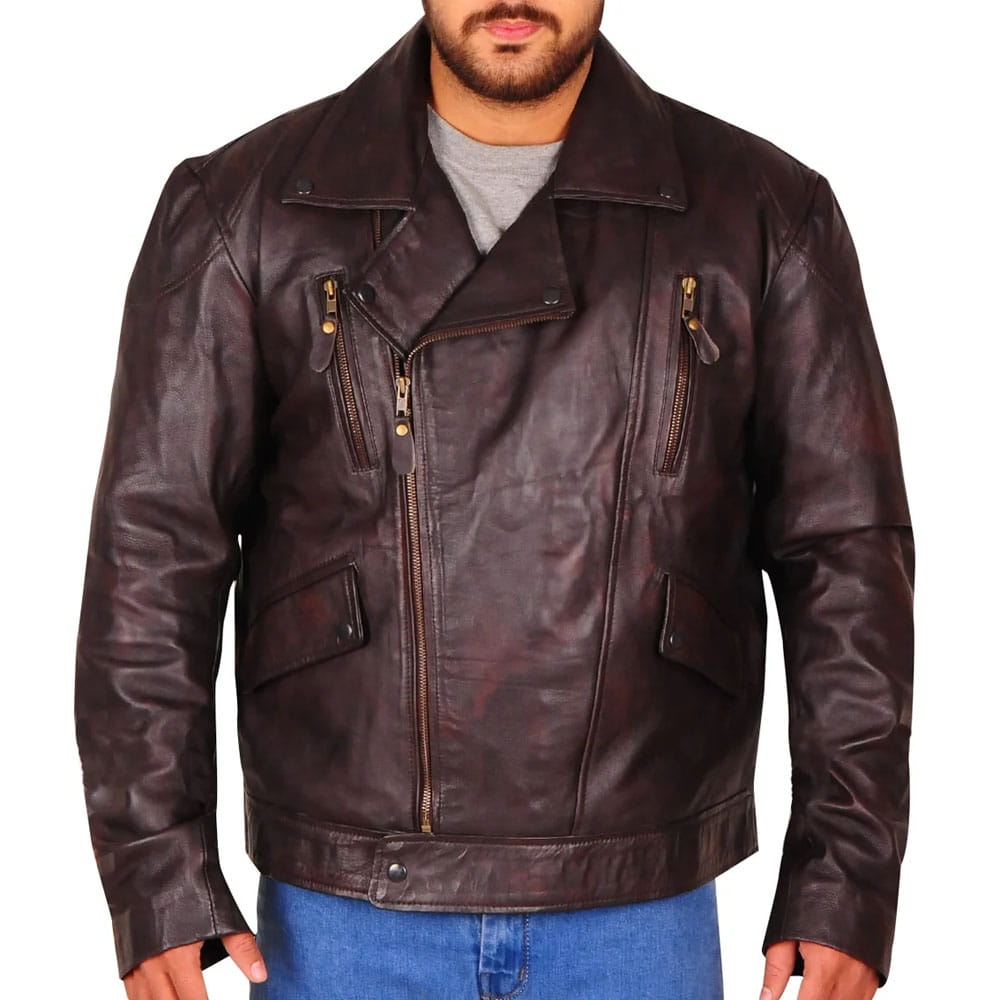A man wearing a dark brown leather motorcycle jacket with a distressed finish, featuring an asymmetrical zipper, zippered chest pockets, and a pointed collar, paired with a gray t-shirt and blue jeans.