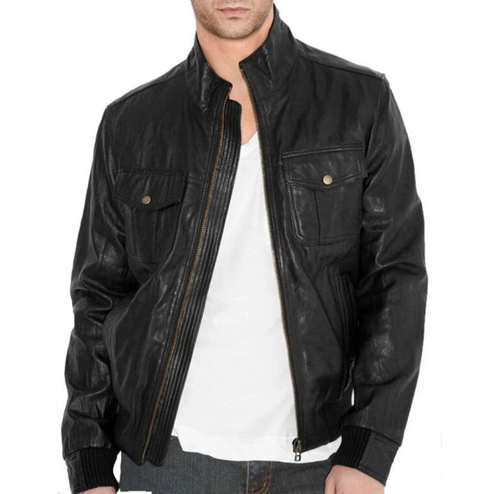 A man wearing a black leather jacket over a white t-shirt and jeans, shown from the chin down against a plain white background.