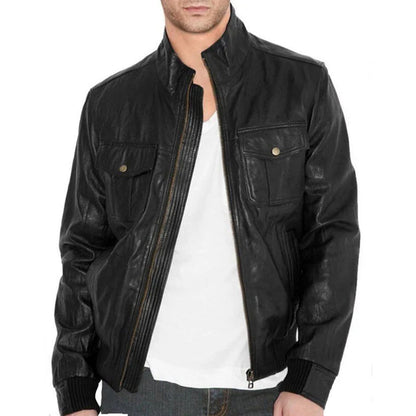 A man wearing a black leather jacket over a white t-shirt and jeans, shown from the chin down against a plain white background.