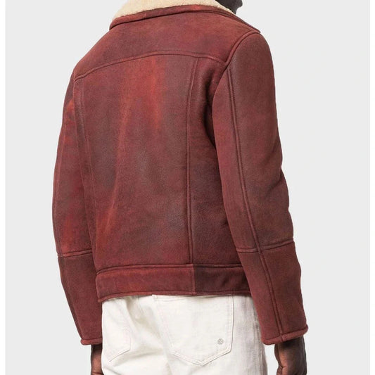 A person shown from the back wearing a dark reddish-brown suede or shearling-style jacket with a light beige collar, paired with off-white pants, against a plain light gray background.