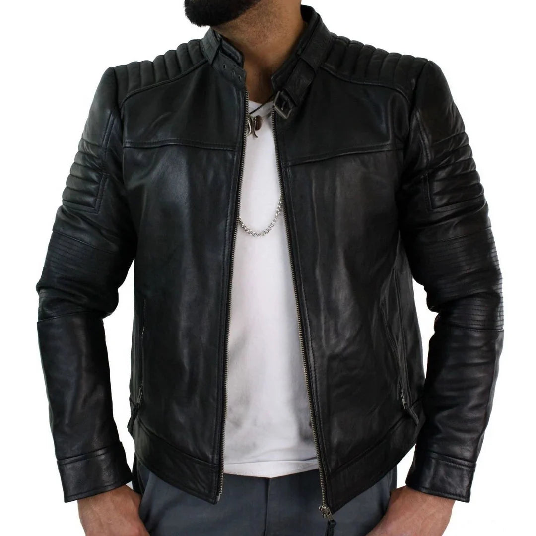 A man wearing a black leather biker jacket with ribbed shoulders and sleeves, styled over a white t-shirt and gray pants against a white background.