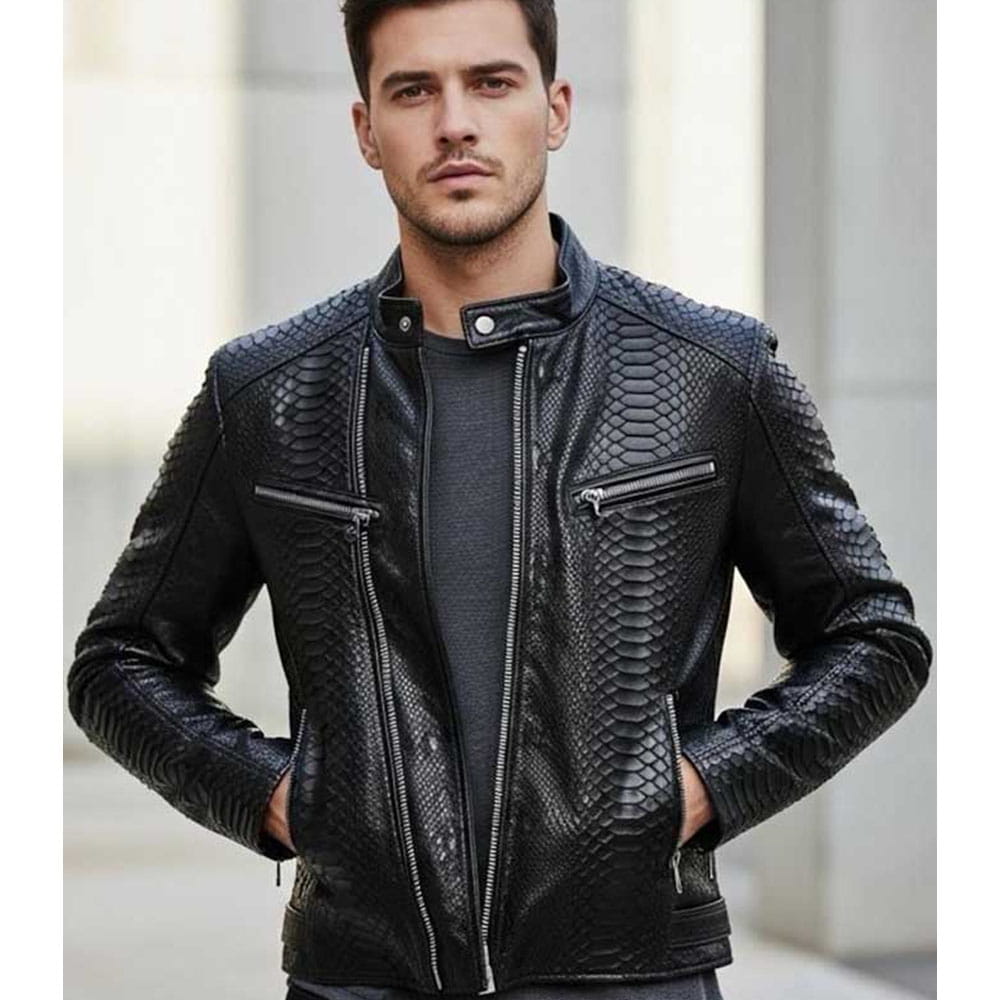 A man wearing a black textured faux-leather moto jacket with a biker-style collar, zippered chest pockets, and a front zipper, photographed against a blurred light gray outdoor background.