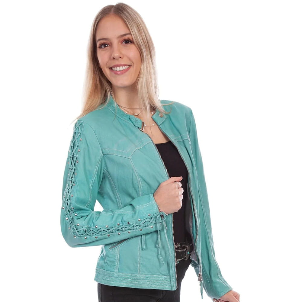 A woman modeling a light teal/mint green moto jacket with lace-up sleeve details, worn over a black top against a plain white background.