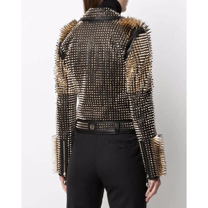 A model shown from the back wearing a black studded leather jacket with gold-toned spiked detailing on the shoulders and sleeves, paired with black trousers.