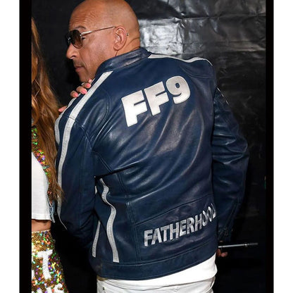 A man wearing a navy blue leather jacket with 'FF9' and 'FATHERHOOD' printed in white on the back, photographed from behind against a dark backdrop.