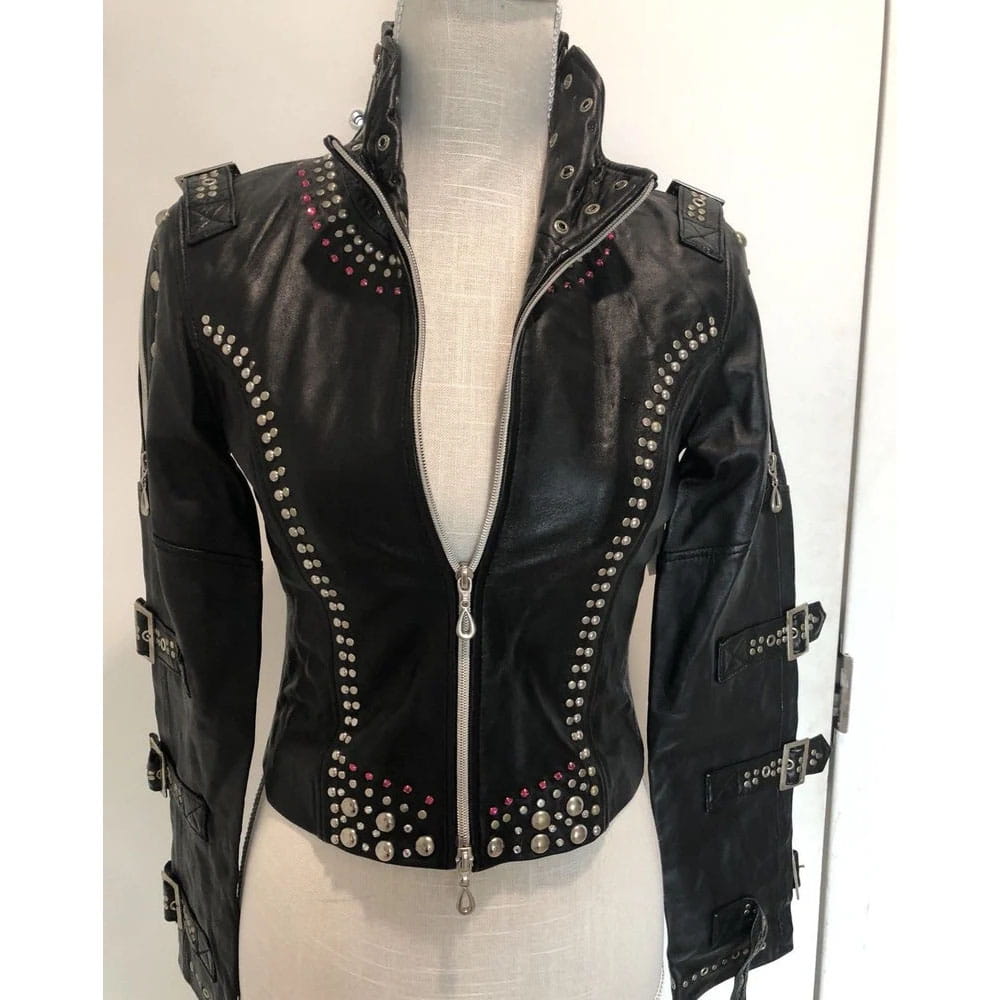 Black faux leather moto jacket with silver studs and buckles, displayed on a mannequin torso.
