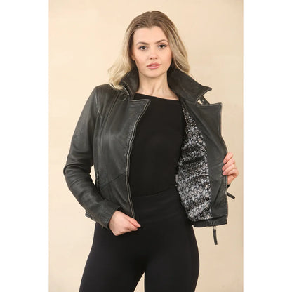 A woman modeling a black faux-leather moto jacket with a black-and-white patterned lining, worn over a black top and black pants against a beige studio background.