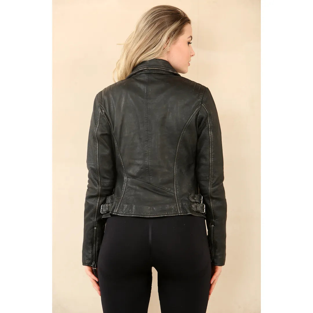 A woman shown from the back wearing a black leather moto jacket with belt details at the waist, paired with black leggings, against a solid beige background.