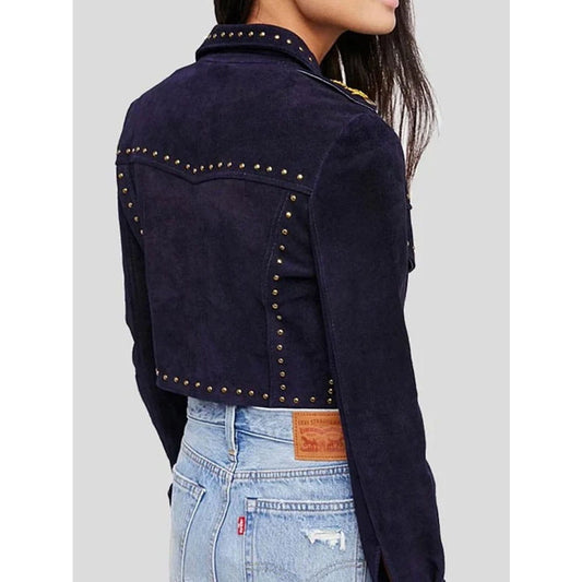 A cropped dark navy blue suede jacket with gold-tone metal studs, shown on a model from the back. The model is also wearing light-wash blue jeans.