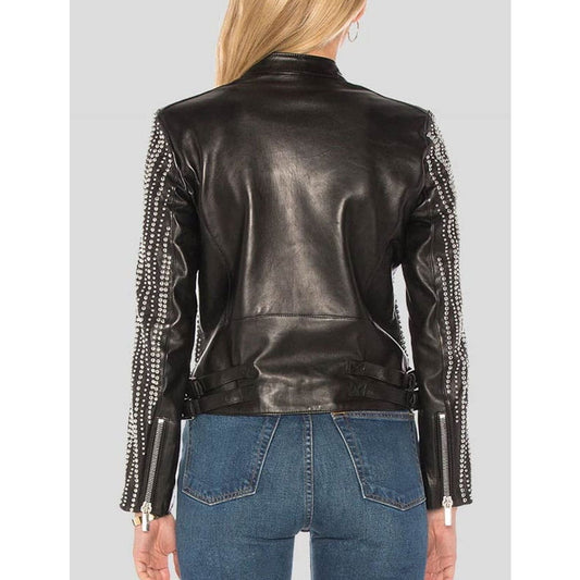 A woman shown from the back wearing a black leather jacket with silver beaded studded sleeve panels and blue jeans, against a light gray studio background.