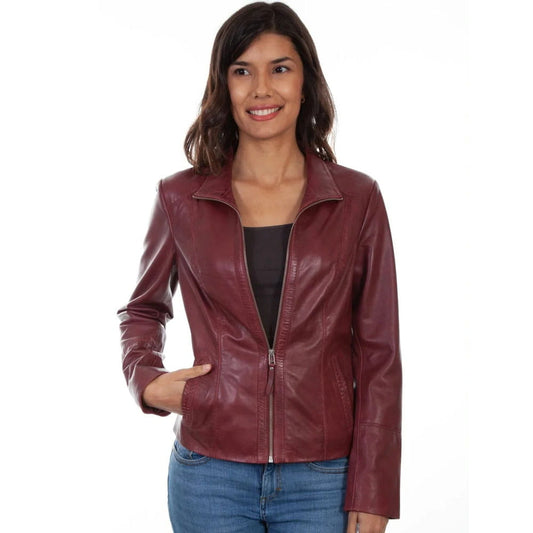 A woman wearing a burgundy faux leather jacket over a black top and blue jeans, standing against a plain white background.