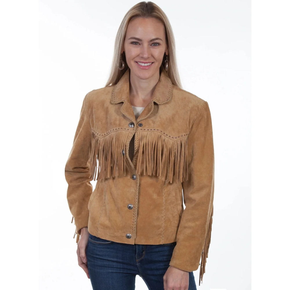 A woman wearing a tan suede fringe jacket and dark blue jeans, standing against a plain white studio background.
