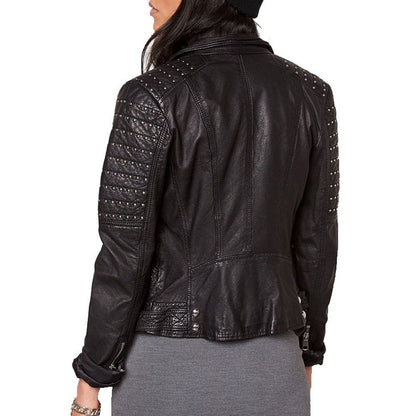 A woman shown from the back wearing a black leather jacket with silver studded details on the shoulders and sleeves, paired with a gray skirt against a white background.