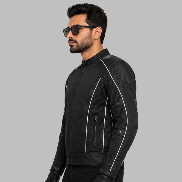 A man wearing a black motorcycle jacket with white contrast stitching, black gloves, and sunglasses, shown in profile against a solid gray background.