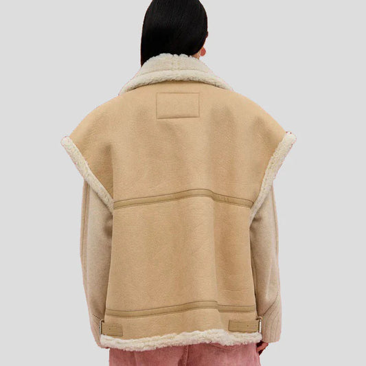 A person shown from the back wearing a beige shearling-lined jacket with a thick cream-colored collar and cuffs, set against a solid light gray background.
