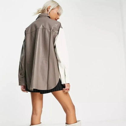 A model shown from the back wearing an oversized taupe faux-leather vest over a white long-sleeve shirt and black pinstriped shorts, against a plain white studio background.