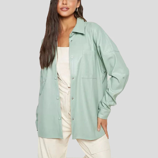 A woman wearing an oversized mint green button-up shirt jacket over a cream top and cream pants, photographed against a solid light gray studio background.